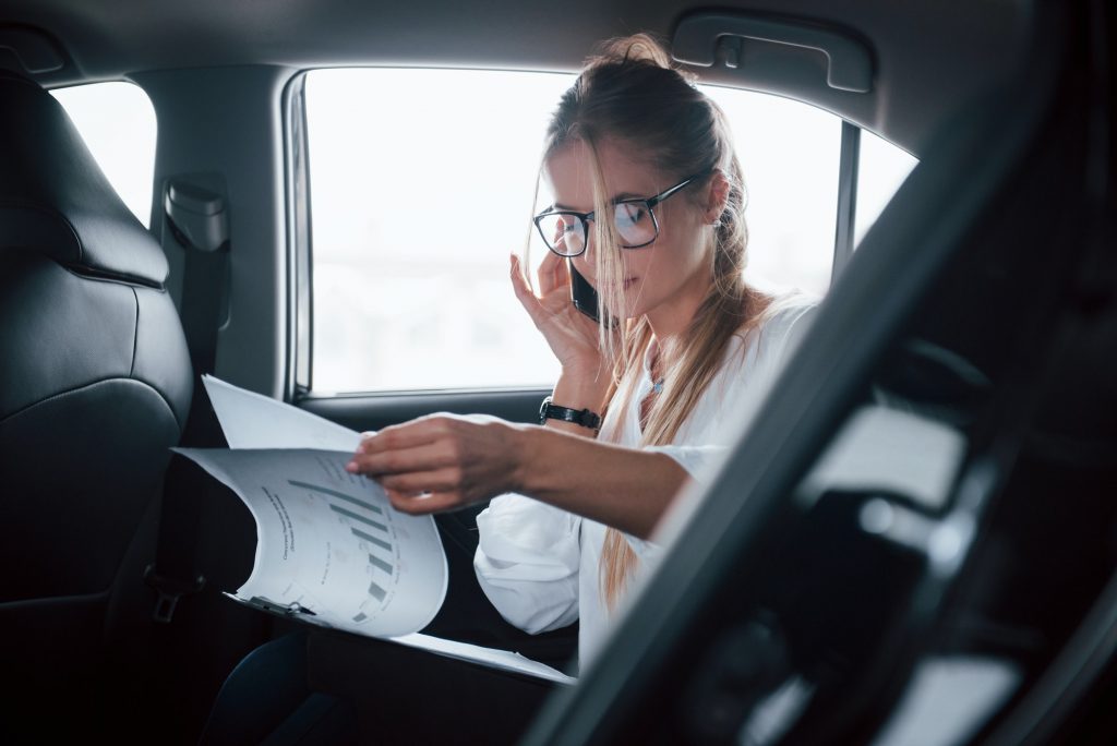 Smart businesswoman sits at backseat of the luxury car with black interior