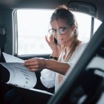Smart businesswoman sits at backseat of the luxury car with black interior